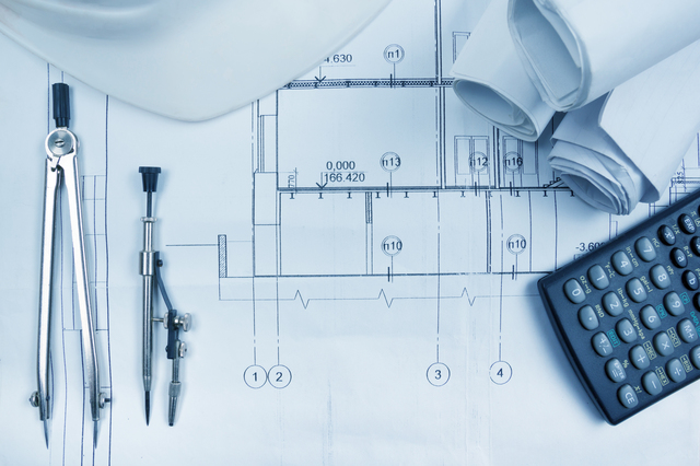 Architectural blueprints, blueprint rolls, compass divider, calculator, white safety on graph paper. Engineering tools view from the top. Copy space. Construction background